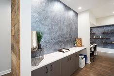 an office with wood flooring and gray wall covering the entire area, along with shelving units