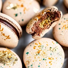 there are many macaroons with gold sprinkles on them and one has a bite taken out