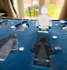 a lego man standing on top of a blue plastic table with water droplets around it