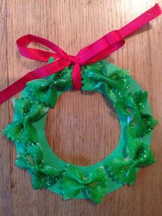 a christmas wreath made out of green plastic and red ribbon on top of a wooden table