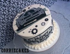 a white cake decorated with black and silver car designs on top of a glass platter