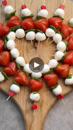 a wooden board topped with tomatoes and marshmallows on top of each other