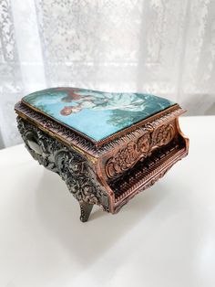 an ornately decorated box sitting on top of a white table next to a curtain