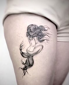 a woman's thigh with a mermaid tattoo on it