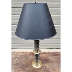 a lamp with a black shade on it sitting on top of a wooden table next to a garage door