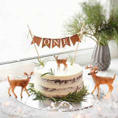 a cake decorated with deer figurines and bunting banner