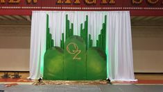 the stage is set up for an event with green and white drapes on it