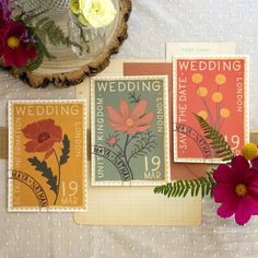 three wedding postcards on a table next to flowers and a vase with an orange flower