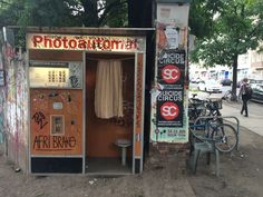 an old phone booth with graffiti on the walls and doors, in front of parked bicycles