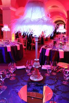 a table topped with lots of purple and white tables covered in wine glasses next to a tall lamp