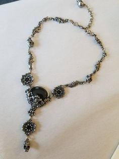 "Black cabochon stone with leaves and skulls with Black crystal eyes Flowers with Black crystal centers & Vitrail crystal details around Adjustable length 14-18\" Lead free pewter Always ethically sourced bones. Nothing has ever been harmed for the purpose of our jewelry. All pieces are made-to-order despite the \"in stock\" number in the listing. Time frame varies from piece to piece so please message us if you need something by a certain date and we will do our best. A portion of our profi Gothic Silver Onyx Necklace, Silver Onyx Gothic Necklace, Silver Necklace With Stone Setting, Gothic Oval Metal Jewelry, Silver Onyx Gothic Jewelry, Gothic Silver Oval Necklace, Victorian Necklace, Crystal Eyes, Cabochon Necklace