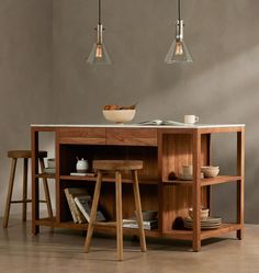 a kitchen island with two hanging lights above it and plates on the counter top next to it