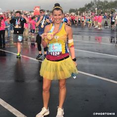 a woman wearing a yellow tutu and running in a marathon with other people behind her