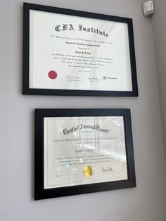 two framed diplomas are hanging on the wall next to each other in black frames