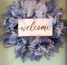 a welcome sign is hanging on a mesh wreath with blue and white ribbons around it