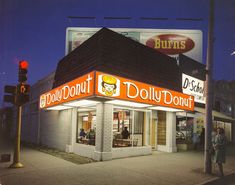 an old photo of a doughnut shop at night with people standing outside the building