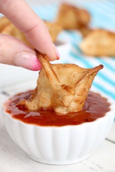 a person dipping something into a small bowl filled with ketchup and cheese chips