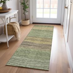 a green rug on the floor in front of a white door with a potted plant next to it