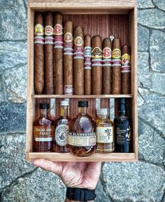 a person holding up a wooden box filled with cigars