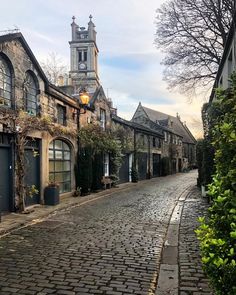 a cobblestone street with old buildings and a clock tower in the background