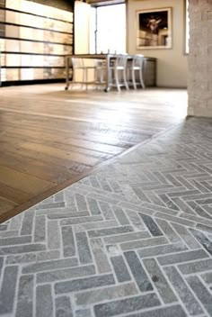 an empty room with wood floors and tile flooring on the ground in front of a brick wall