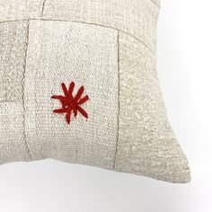 a white pillow with red embroidered design on the front and back, against a white background