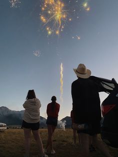 three people watching fireworks in the sky with their backs turned to look at them,