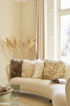 a living room with a white couch and some pillows on the back of it's seat