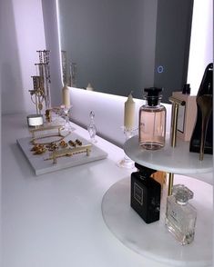 two white trays with perfume bottles and candles on them sitting on a counter in front of a mirror