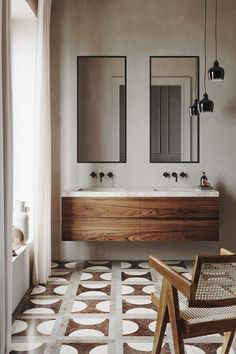 a bathroom with two sinks, mirrors and a chair in front of the mirror on the wall