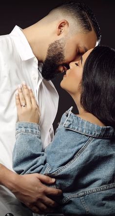 a man and woman kissing each other in front of a black background