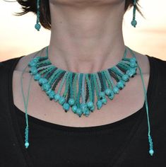 a woman wearing a blue necklace and matching earring with turquoise beads on her neck