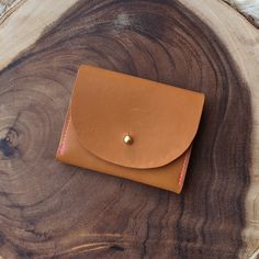 The Juno wallet is perfect for cards and cash. It has 3 sections total with the middle section being perfect for loose change. The coins won't fall out! Promise. Exterior is made from our American-made oil tanned leather in tan. Accents in peach suede. Brass button closure. Measures 4" wide by 3" high. Cognac Trifold Wallet With Card Slots For Everyday Use, Trifold Coin Purse For Everyday Use, Leather Trifold Coin Purse With Card Slots, Orange Leather Wallet For Daily Use, Everyday Cognac Bifold Wallet, Orange Leather Wallet With Card Slots, Orange Leather Wallets With Interior Card Slots, Leather Trifold Coin Purse With Interior Card Slots, Trifold Leather Coin Purse With Card Slots