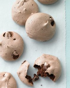 three chocolate cookies with one broken in half on a piece of parchment paper next to it