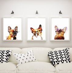 three framed pictures on the wall above a white couch with pillows and black and white throw pillows