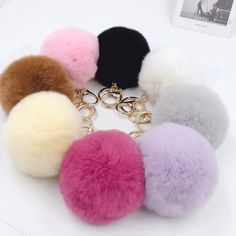 six pom - poms on a white surface with a black, pink, purple, and yellow keychain