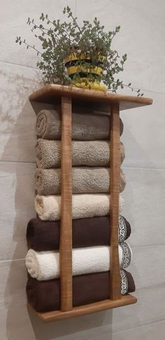 a wooden shelf with towels and a potted plant on it, hanging from the wall