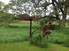 a rusted bike sitting in the middle of a lush green field next to a tree