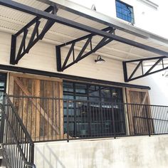 an outside view of a building with wooden doors and metal railings on the second floor