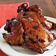 two pieces of chicken on a white plate with red placemat and wooden table in the background