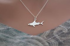 a silver necklace with a shark on it