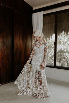 a woman in a wedding dress looking out the window