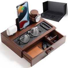 an iphone is sitting on top of a wooden box with glasses and other items in it