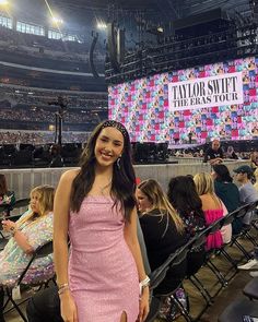 a woman in a pink dress standing next to a crowd at a convention or show