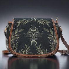 "Boho Forest witch Black Vegan leather saddle bag, women magic fern crossed body purse, cute PU leather hand bag goth bag, hippies boho gift This cute boho saddle Crossbody Bag is a great way to intrude Cottagecore styles into your everyday wardrobe. The purse is great for everyday use with an adjustable strap that can take it from Saddle bag style to Sling bag style. This vegan leather cute crossbody bag is just what you need for a little extra room for your stuff.  Made from quality materials Bohemian Crossbody Saddle Bag, Bohemian Crossbody Saddle Bag For Daily Use, Bohemian Crossbody Saddle Bag With Adjustable Strap, Bohemian Satchel Saddle Bag With Adjustable Strap, Bohemian Saddle Bag Satchel With Adjustable Strap, Bohemian Saddle Bag With Adjustable Crossbody Strap, Bohemian Shoulder Saddle Bag With Adjustable Strap, Goth Bag, Wolf Shifter