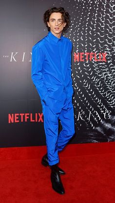 a man in a blue suit standing on a red carpet