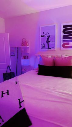 a bed with pink sheets and pillows in a room that has pictures on the wall