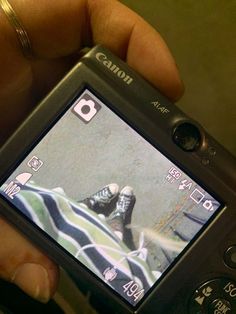 a person holding a cell phone in their hand with the screen showing a man's feet