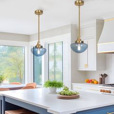 a kitchen with blue cabinets and an island in front of a window that has plants on it