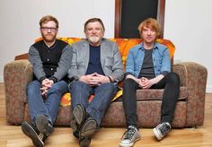 three men sitting on top of a couch next to each other